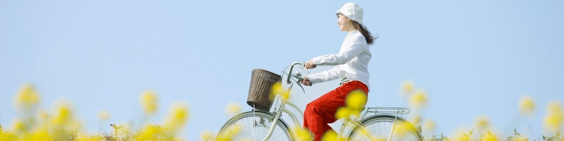A young woman rides a bicycle through a summer field