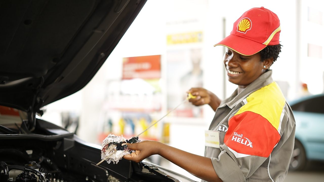 An enginner pours Shell lubricant into a car engine
