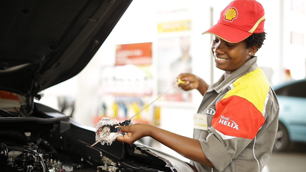 An enginner pours Shell lubricant into a car engine