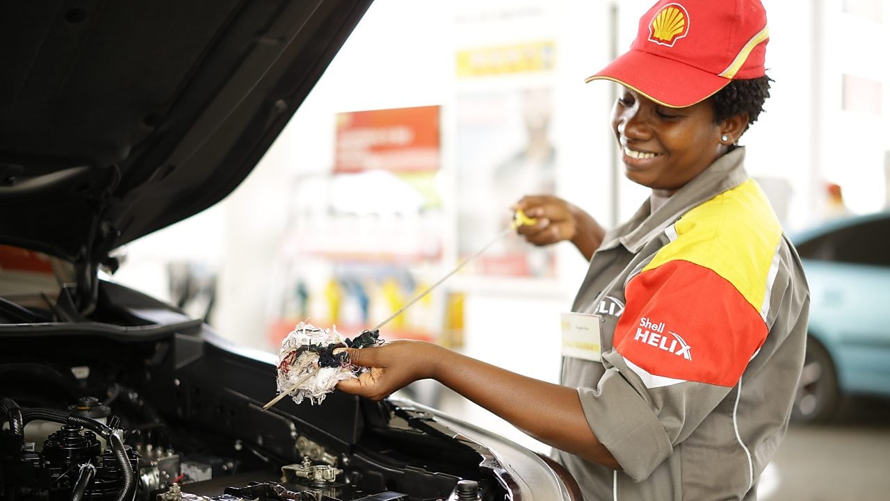 An enginner pours Shell lubricant into a car engine